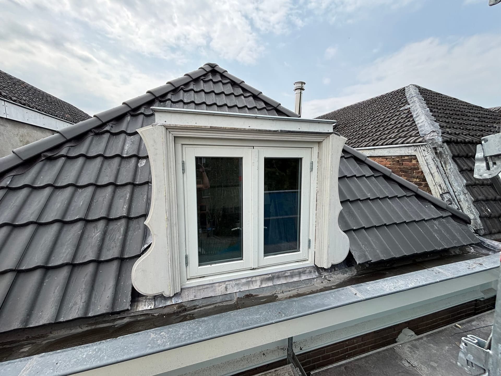 Oude witte dakkapel op een pannendak