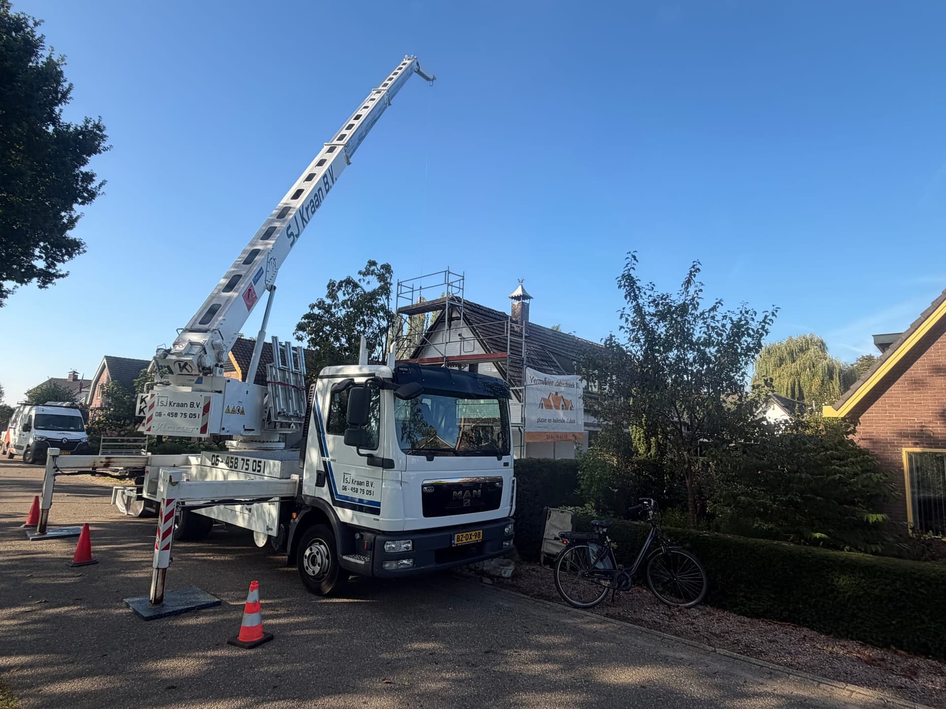 Kraan met uitgeschoven giek bij een woning