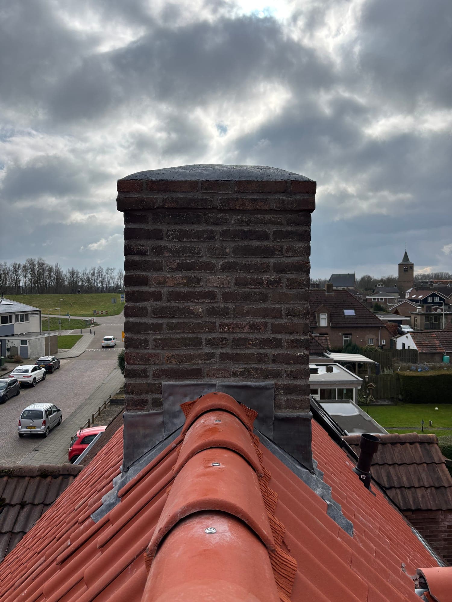 Schoorsteen met nieuw loodwerk op een rood pannendak