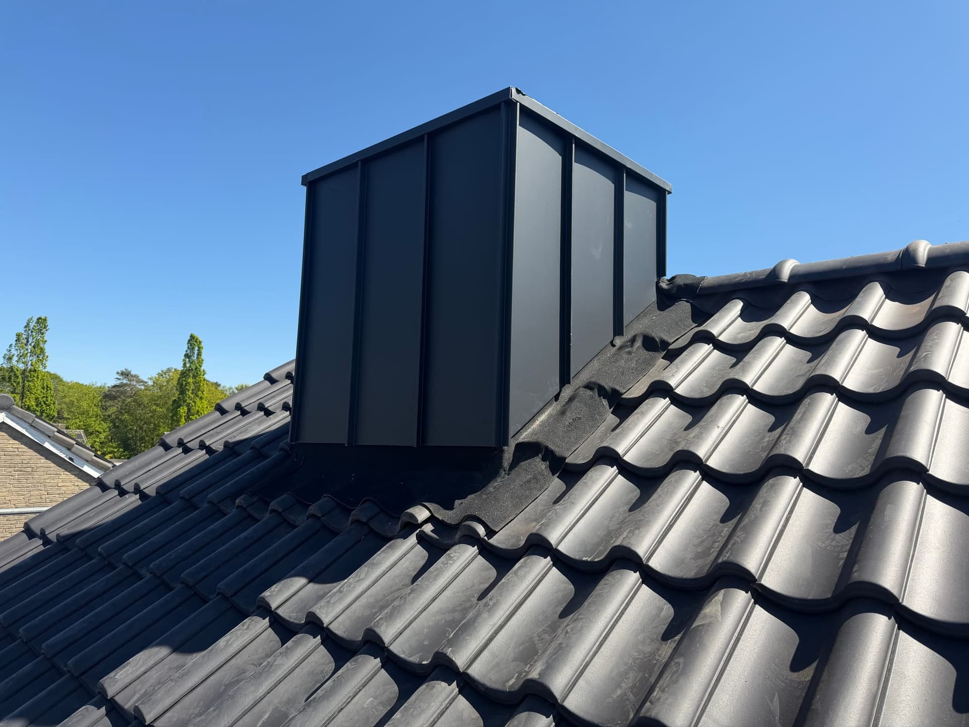 Schoorsteen met zinken bekleding tussen de dakpannen